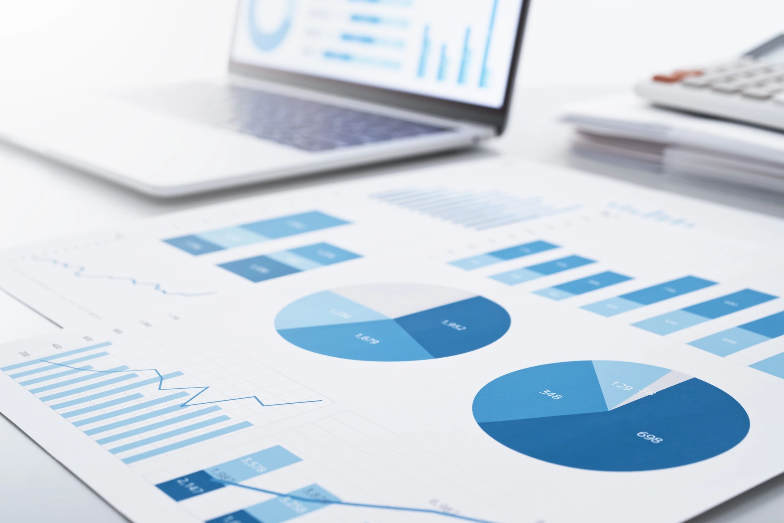 Business reports and laptop with charts for consulting and analysis