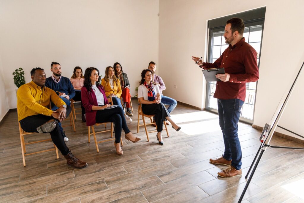 Businessman standing by a whiteboard and holding a presentation for a group of his coworkers